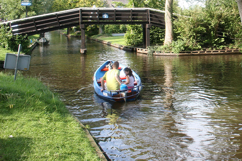 Ouder met kind varen in fluisterbootje in Giethoorn